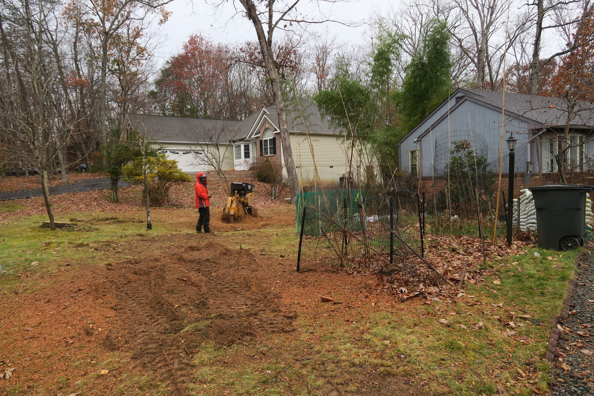 A man is cutting a tree stump with a chainsaw.