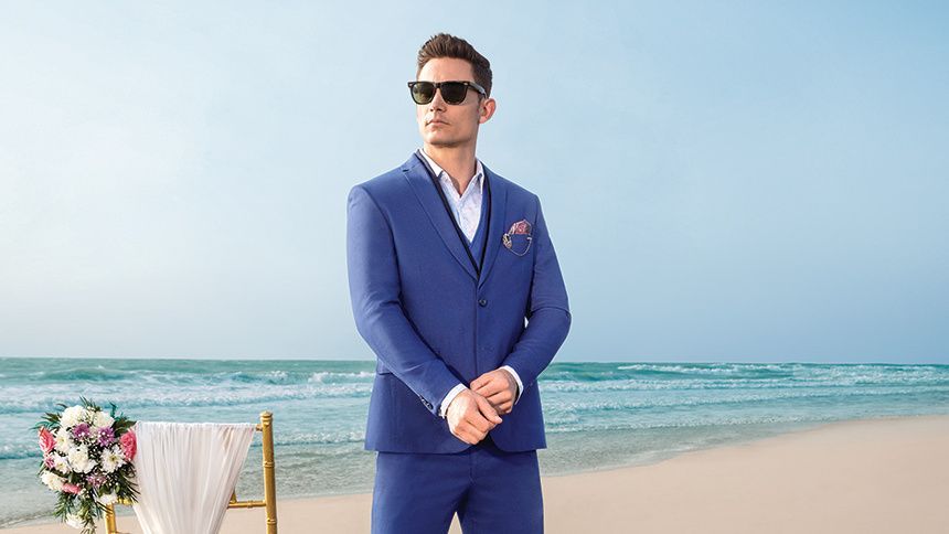 A Man in A Blue Suit and Sunglasses Is Standing on A Beach — New Park Suit Hire & Menswear in Cairns, QLD