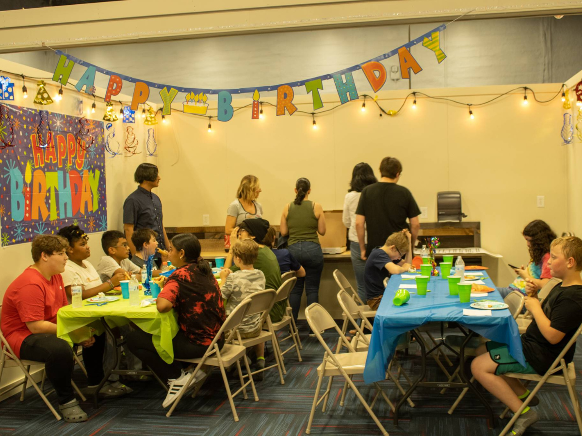 A group of people are sitting at tables at a birthday party.