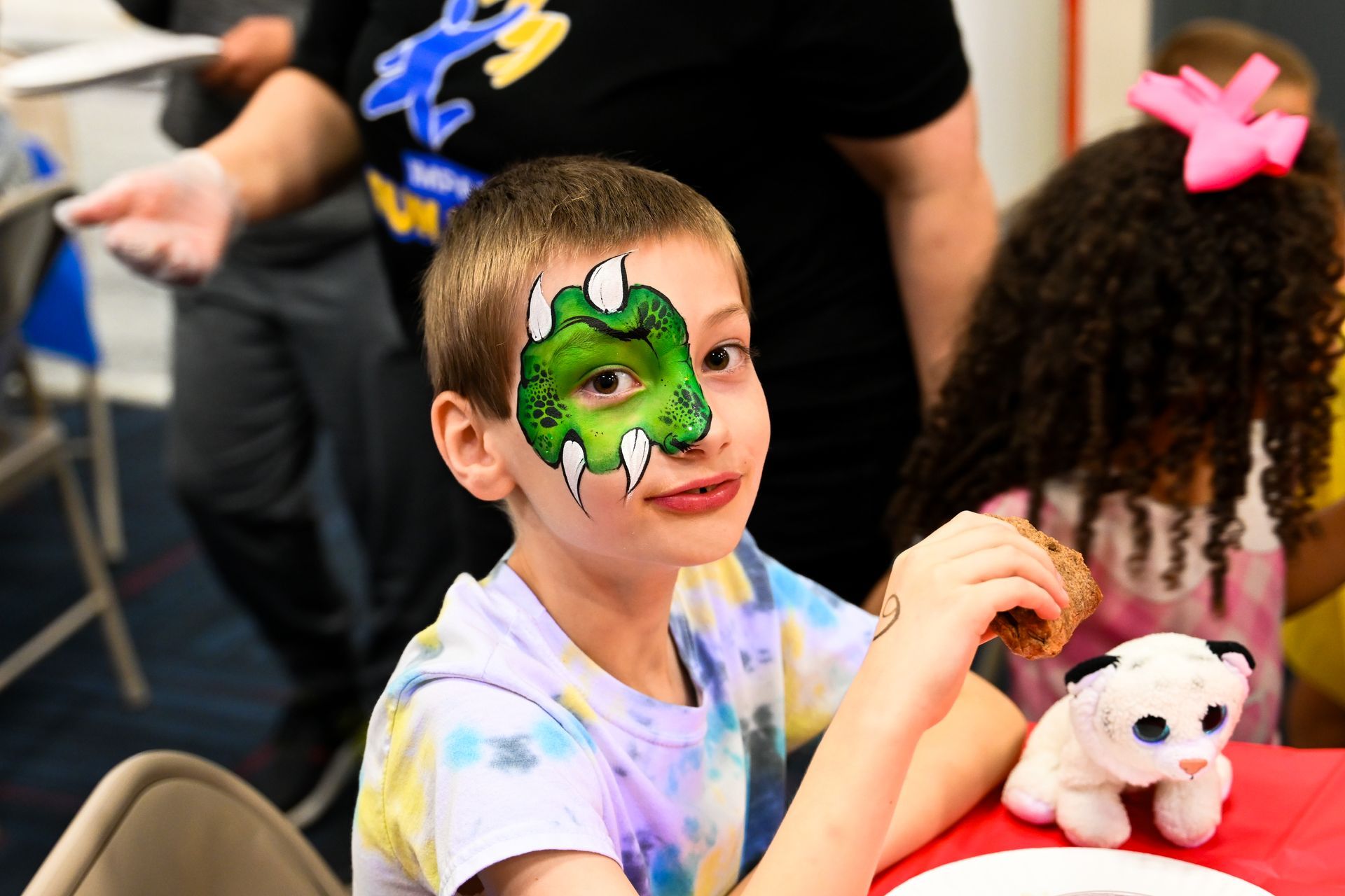 A young boy with his face painted like a dinosaur at Impact Fun Zone