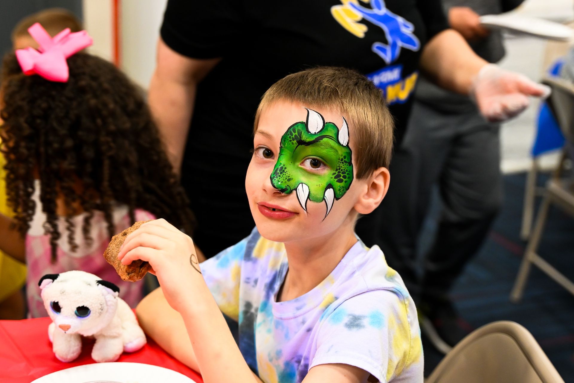 A young boy with his face painted like a dinosaur at Impact Fun Zone