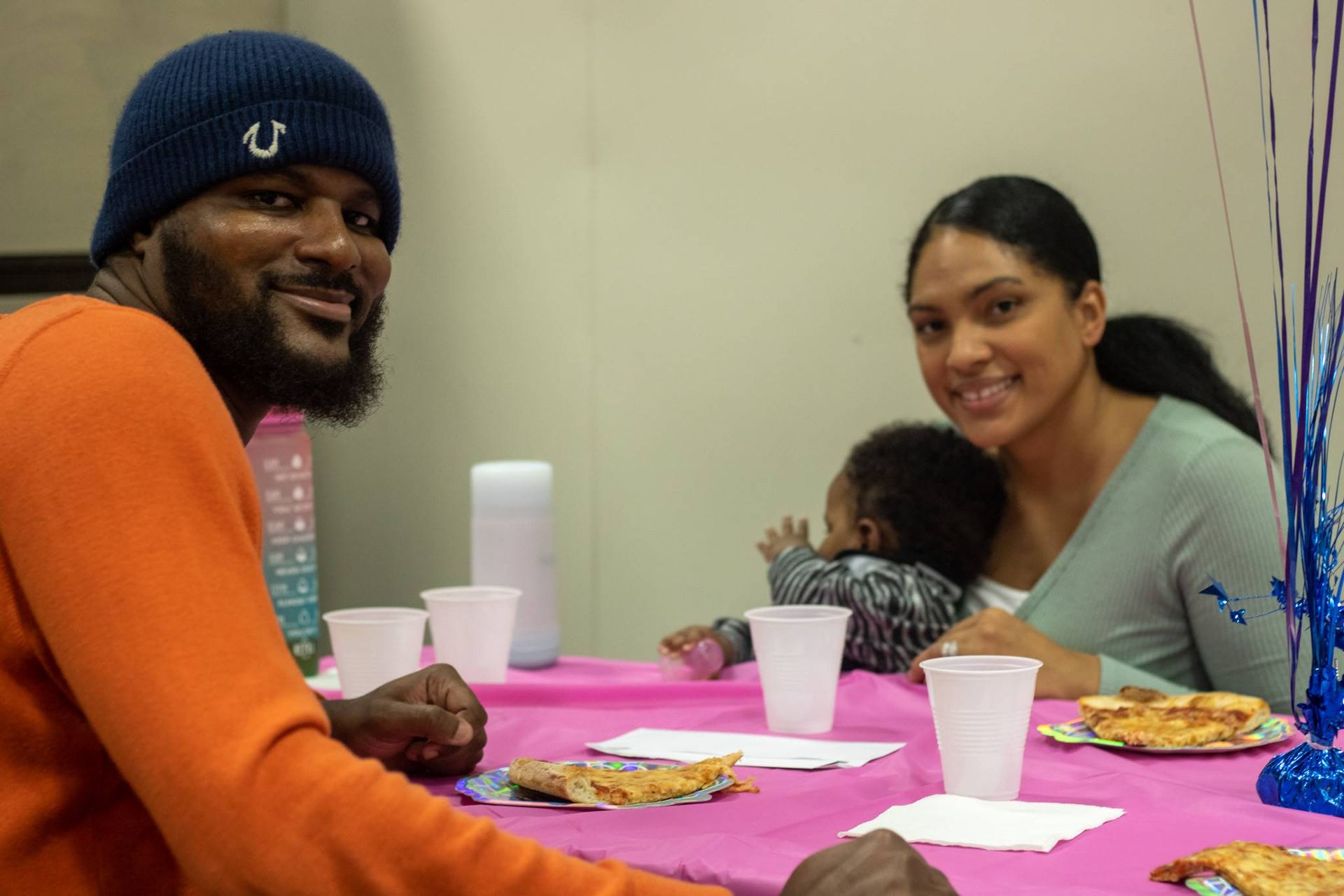 A man wearing a beanie sits at a table with a woman and child at Impact Fun Zone