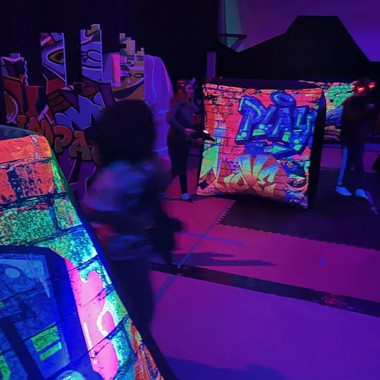 A group of people are standing in a room with glow in the dark graffiti on the wall.