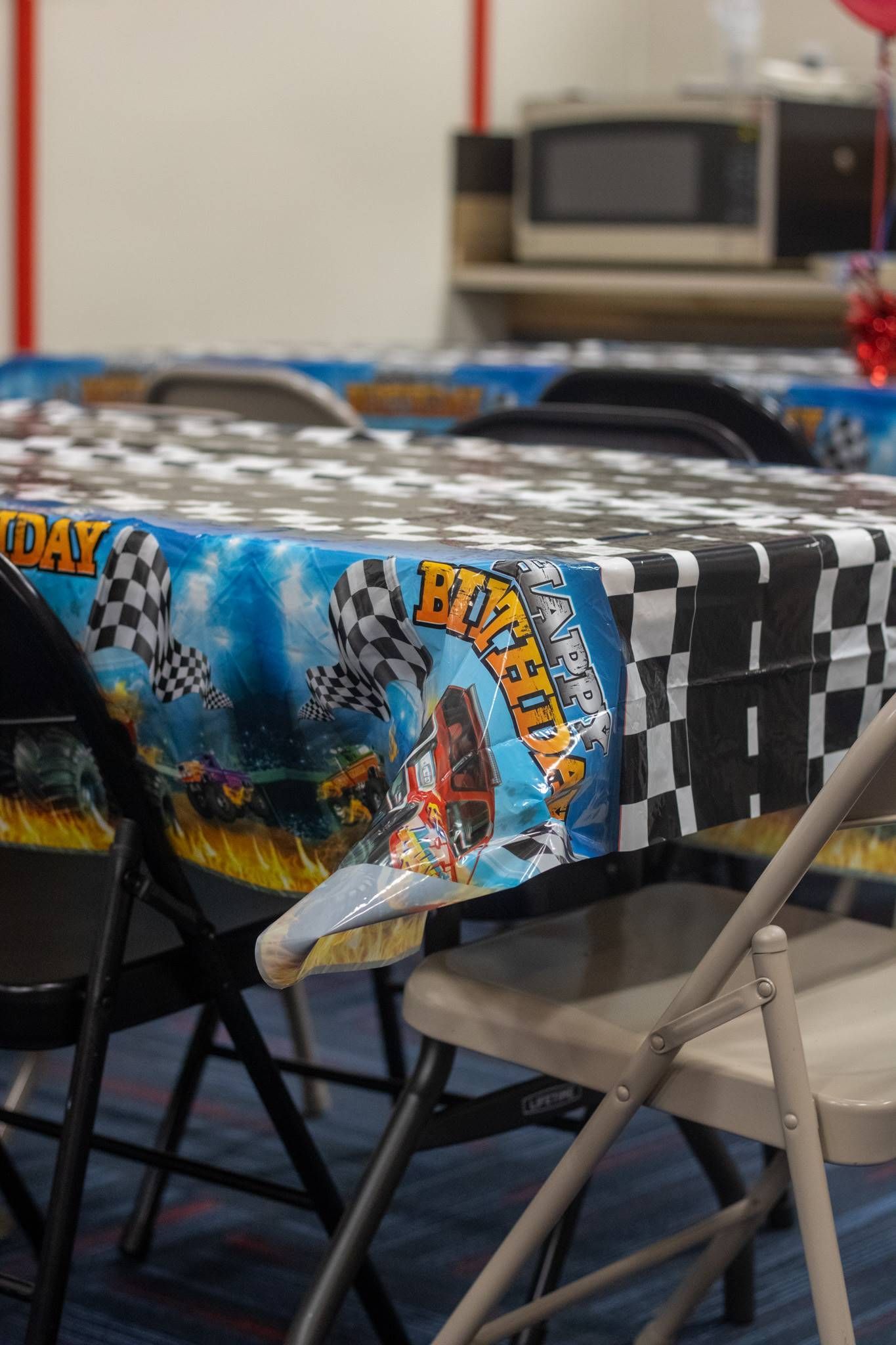 A table with a hot wheels tablecloth and chairs at Impact Fun Zone
