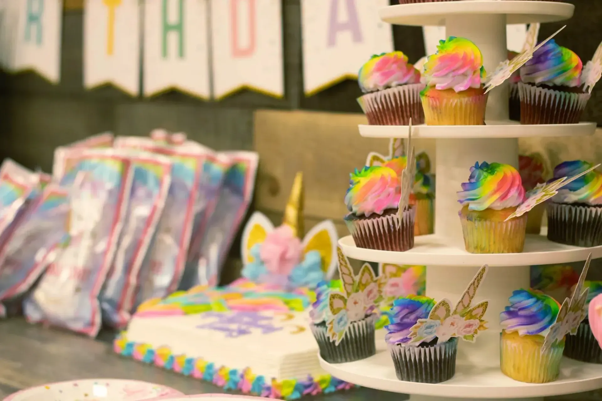 A cupcake tower filled with rainbow colored cupcakes at a unicorn birthday party at Impact Fun Zone