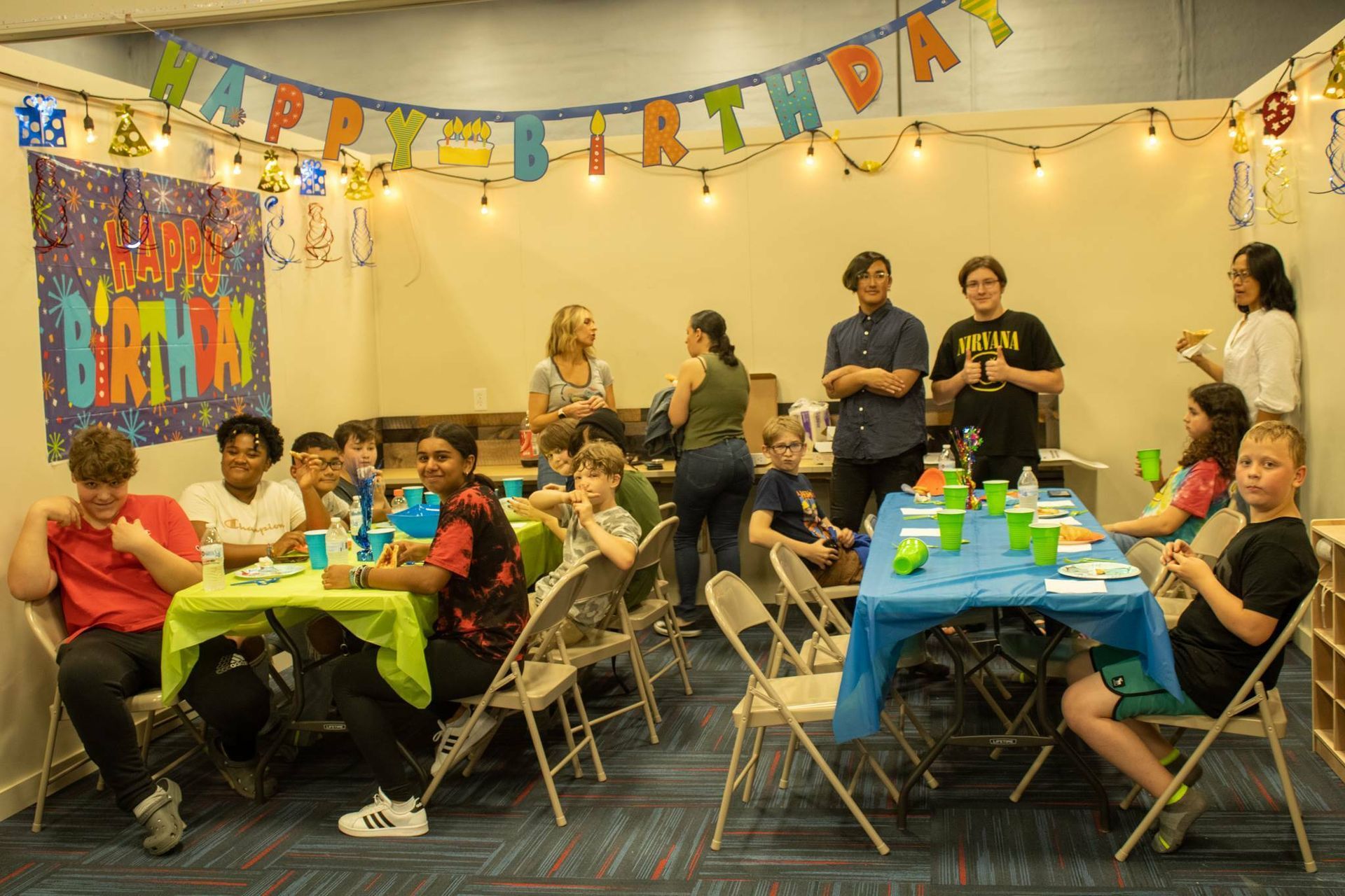 A group of children are sitting at tables at a birthday party at Impact Fun Zone