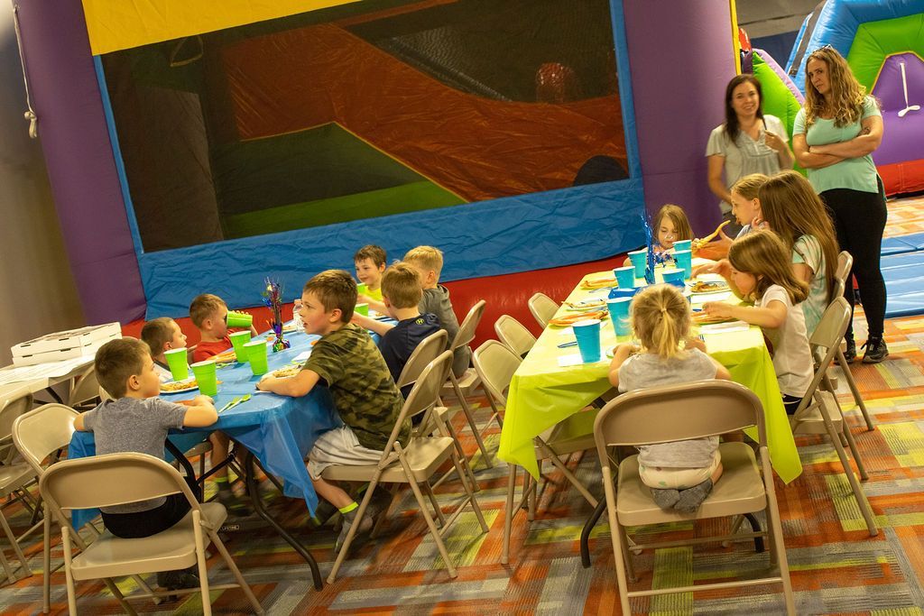 A group of children are sitting at tables at a birthday party at Impact Fun Zone