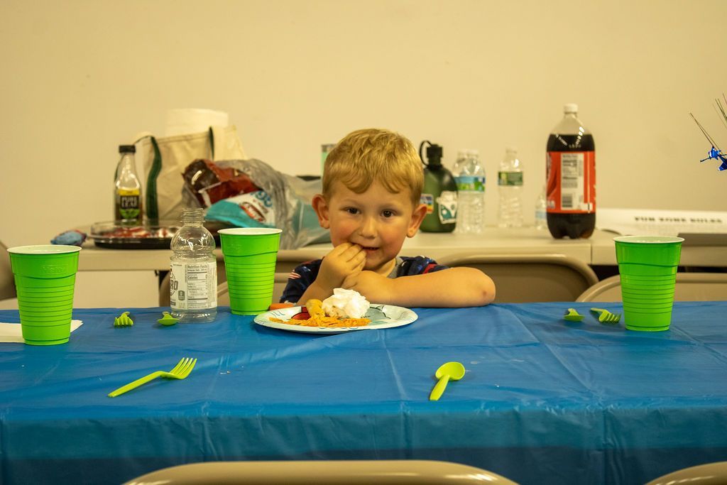 A young boy is sitting at a table with a plate of pizza at Impact Fun Zone