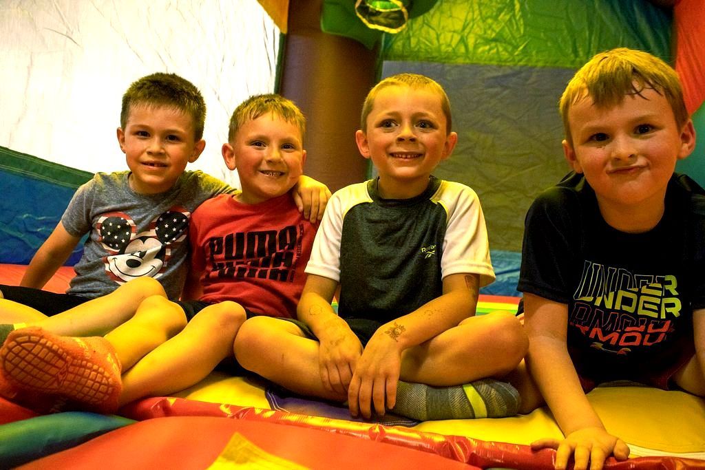 A group of young boys are sitting on a bouncy house at Impact Fun Zone