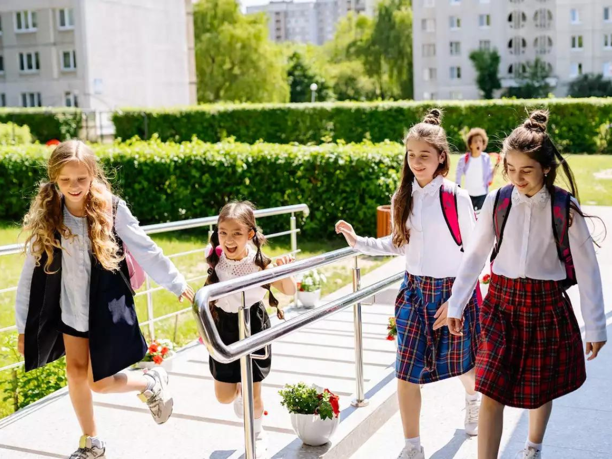 A group of young girls are walking down the stairs of a school building.