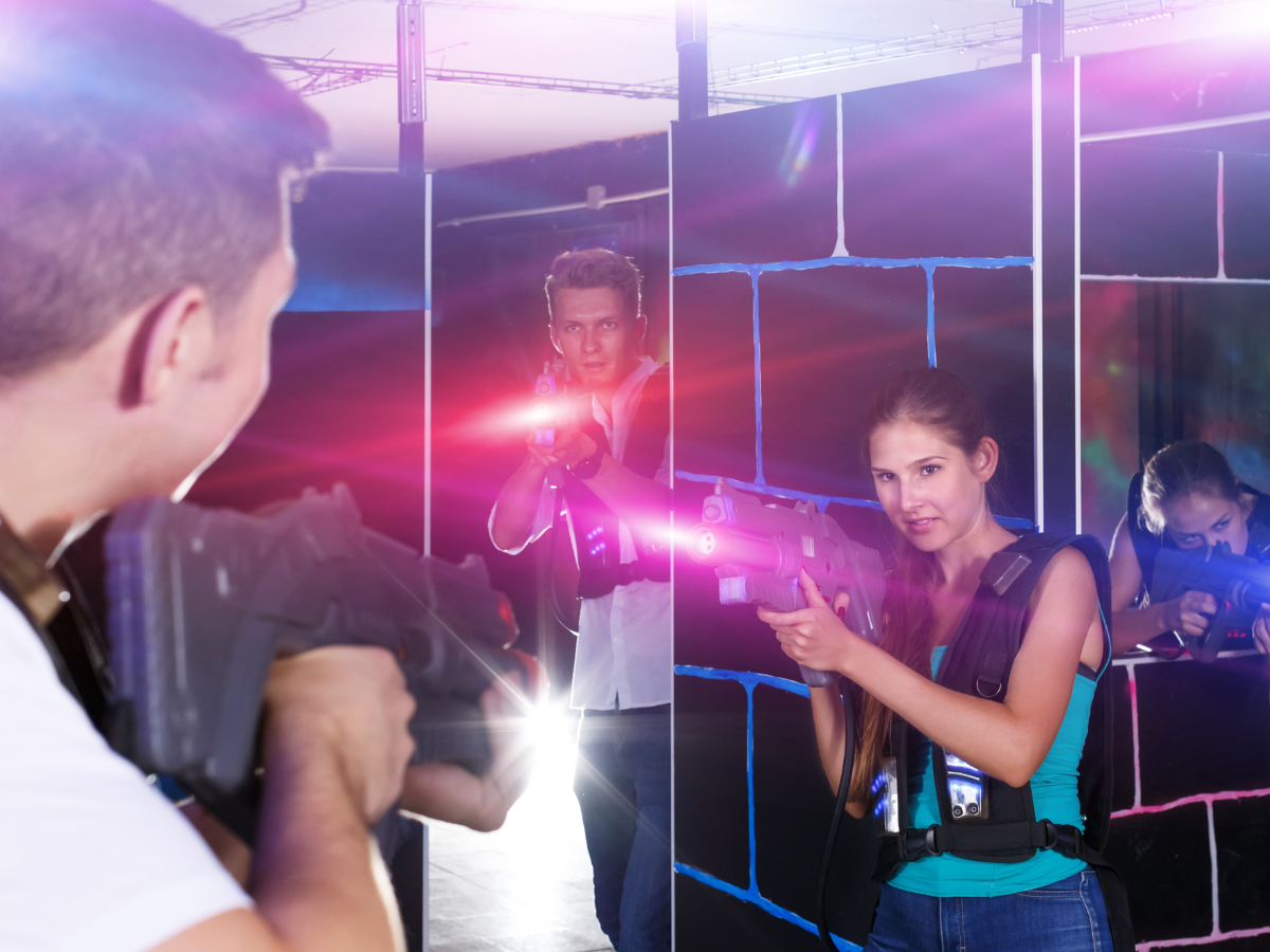 People playing laser tag in a dark arena, aiming their phasers and wearing vests. People playing laser tag in a dark arena, aiming their phasers and wearing vests.