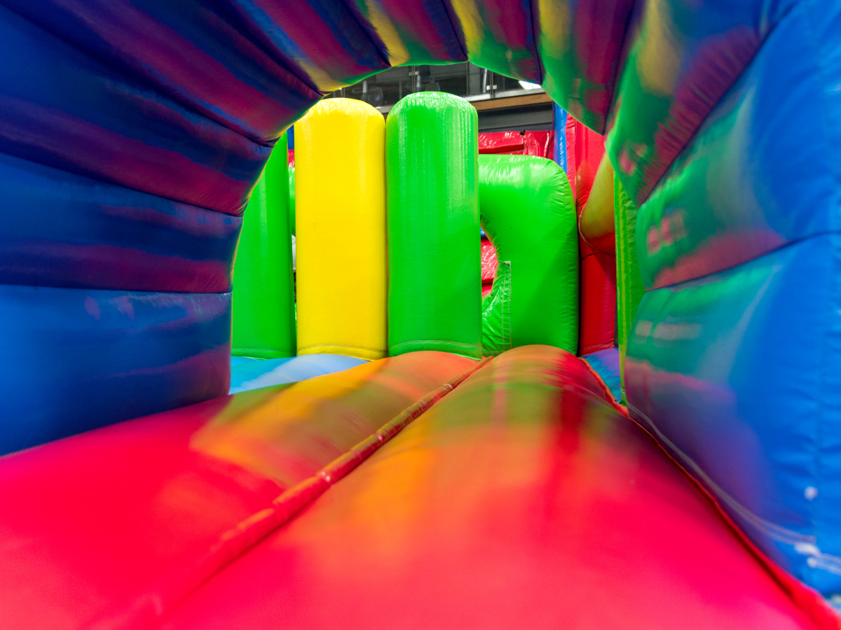 A colorful bouncy house with a slide and a tunnel.