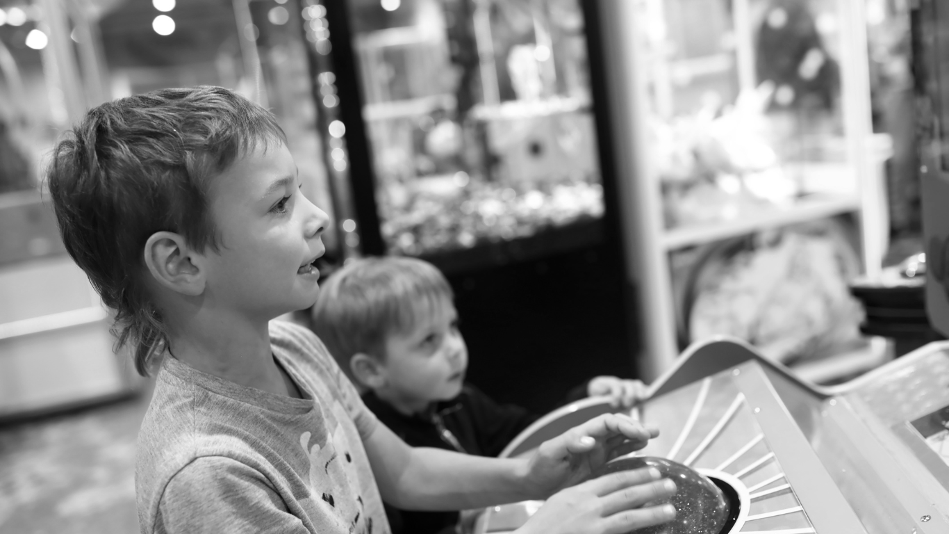 A black and white photo of two young boys playing a game in an amusement park.