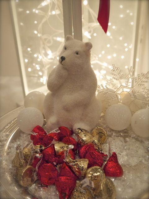 A polar bear is sitting on top of a bowl of kisses.