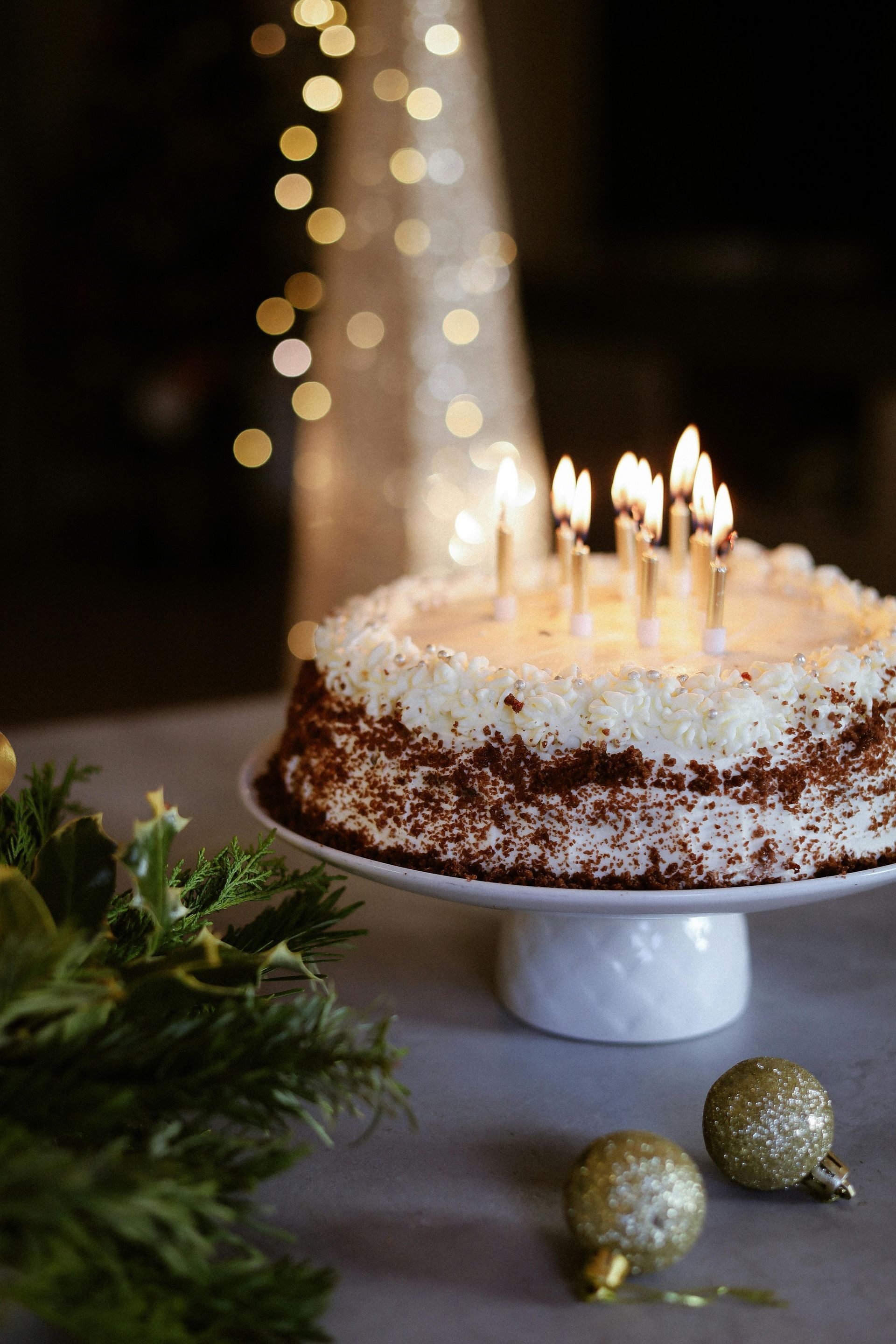 A birthday cake with candles on a white plate on a table.