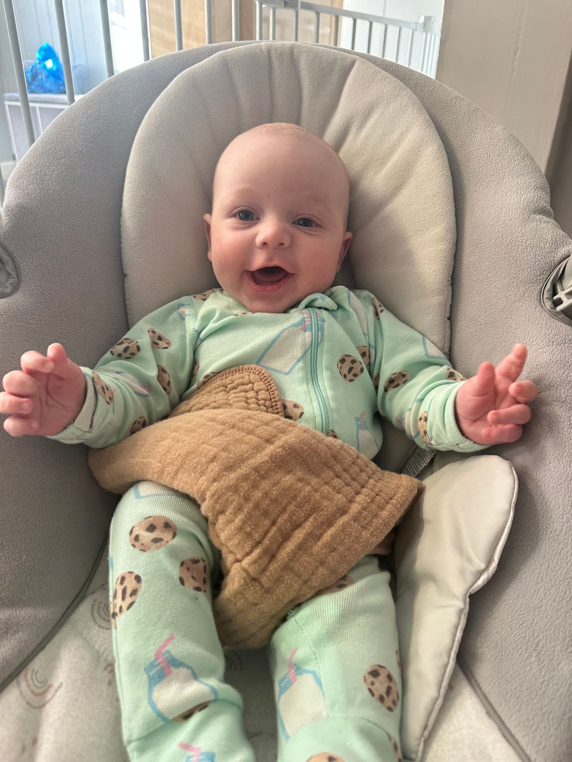 A baby is sitting in a high chair and smiling.