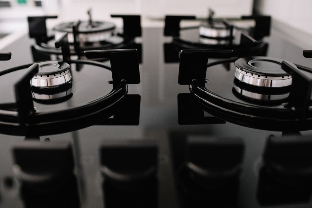 A Close Up of a Gas Stove With Four Burners — Hume Plumbing & Roofing Wollongong in Dapto, NSW