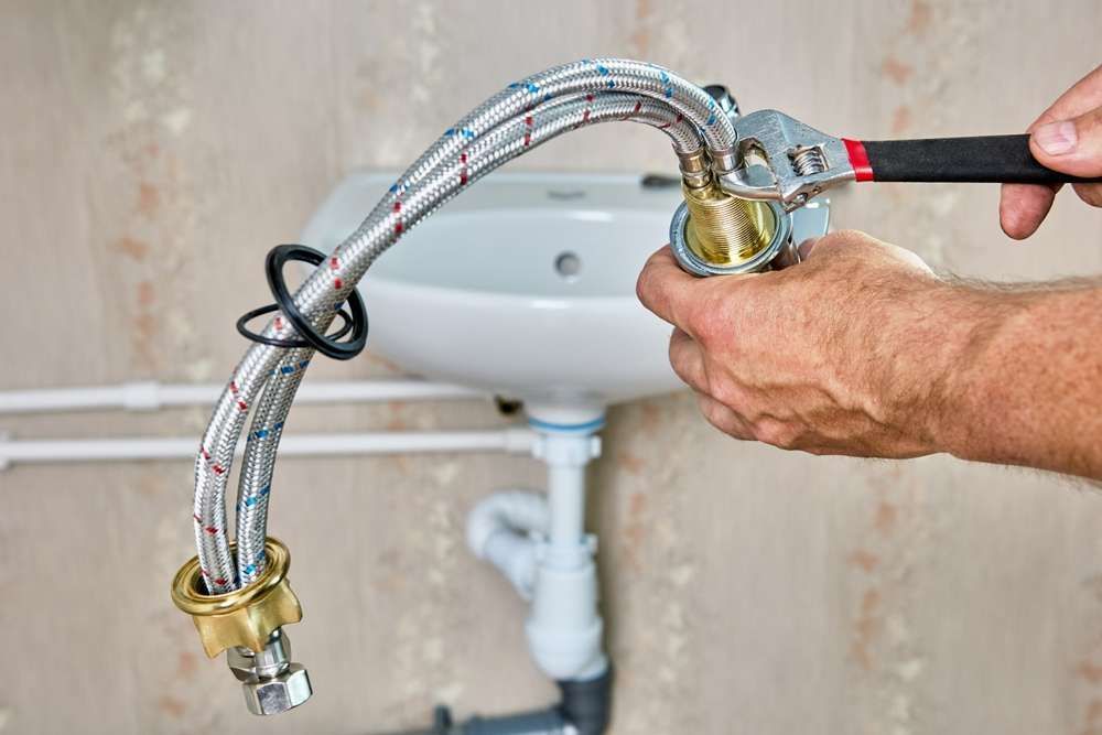 A Plumber is Fixing a Sink Faucet With a Wrench — Hume Plumbing & Roofing Wollongong in Albion Park, NSW