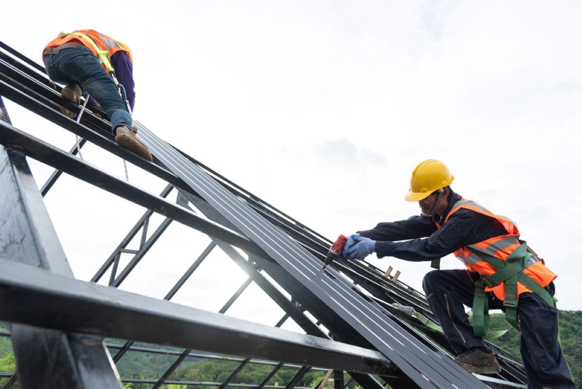 Two Construction Workers Are Working on the Roof of a Building — Hume Plumbing & Roofing Wollongong in Wollongong, NSW