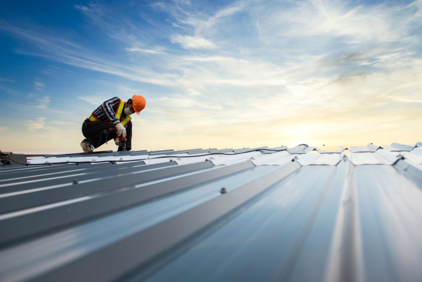 A Construction Worker is Working on a Metal Roof — Hume Plumbing & Roofing Wollongong in Thirroul, NSW
