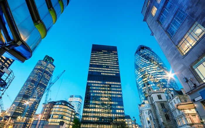 Looking up at a group of tall buildings in a city at night.