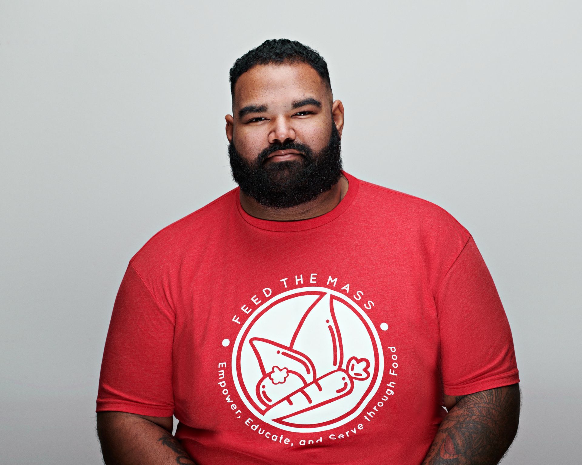 Man with a full beard wearing a red shirt that says