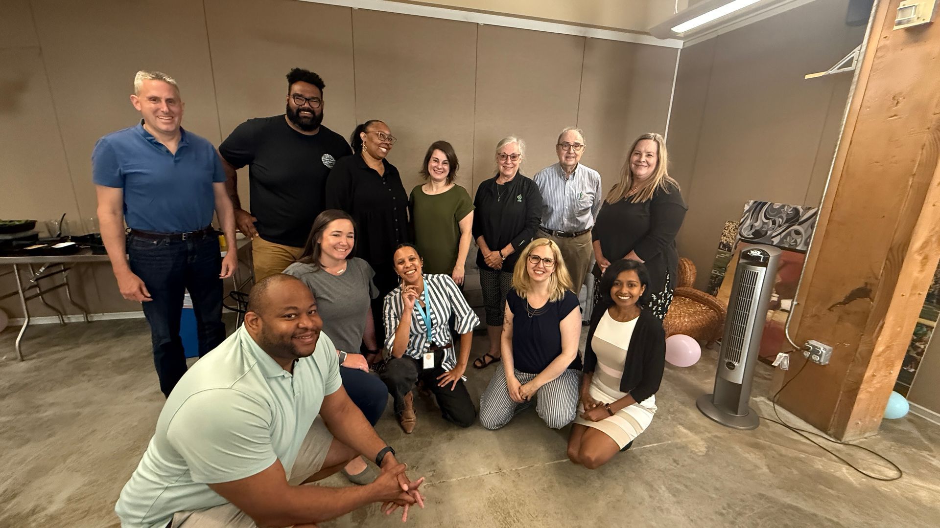 People in a workshop setting; several seated, facing the camera, others in the background, possibly a presentation in progress.