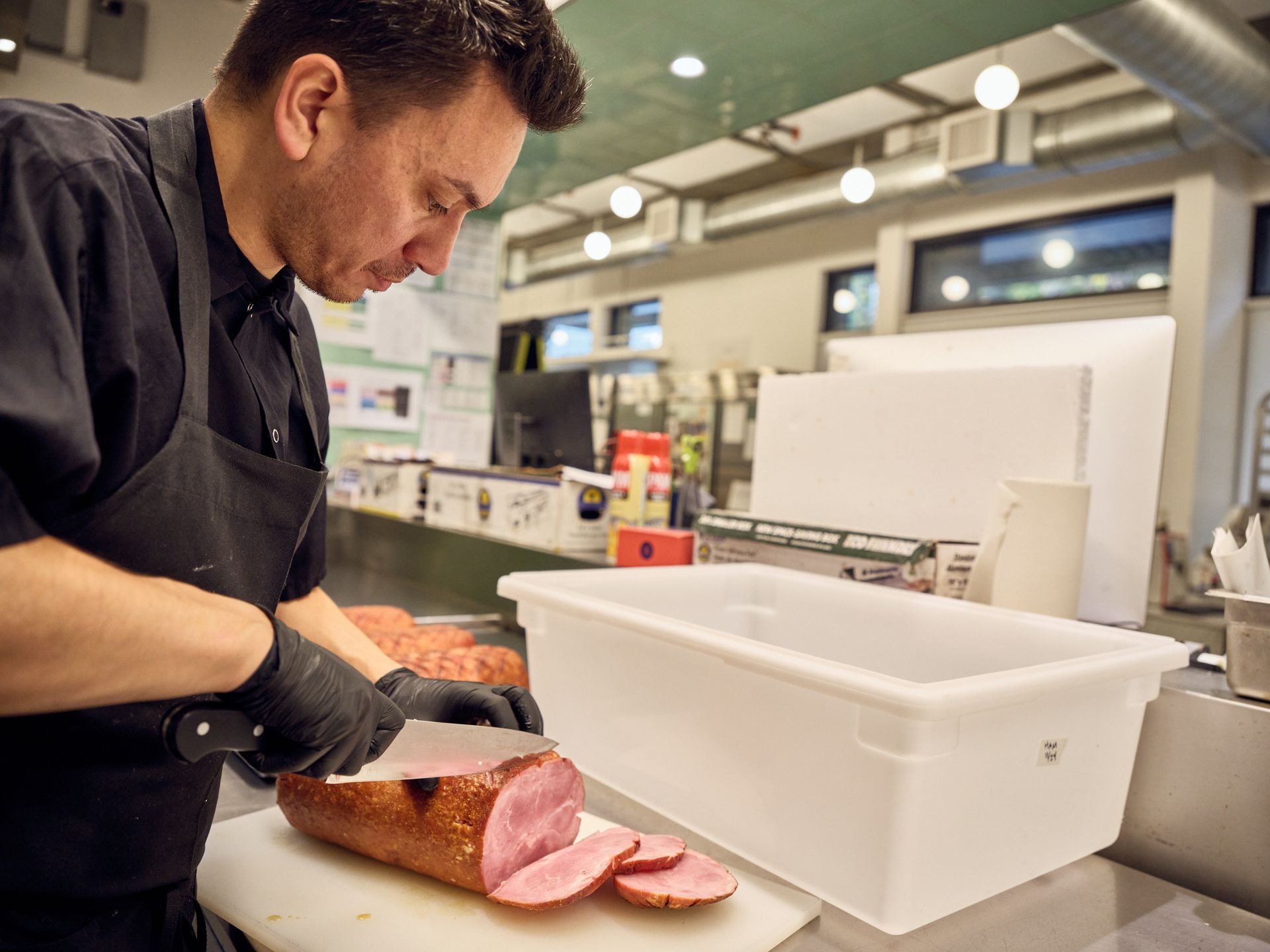Four people in aprons pose in front of a Community Booth, smiling and making gestures; one holds a raccoon puppet.