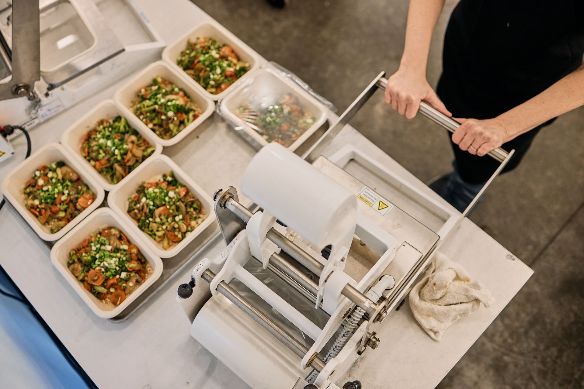 Food service associate seals meals at the Feed the Mass kitchen