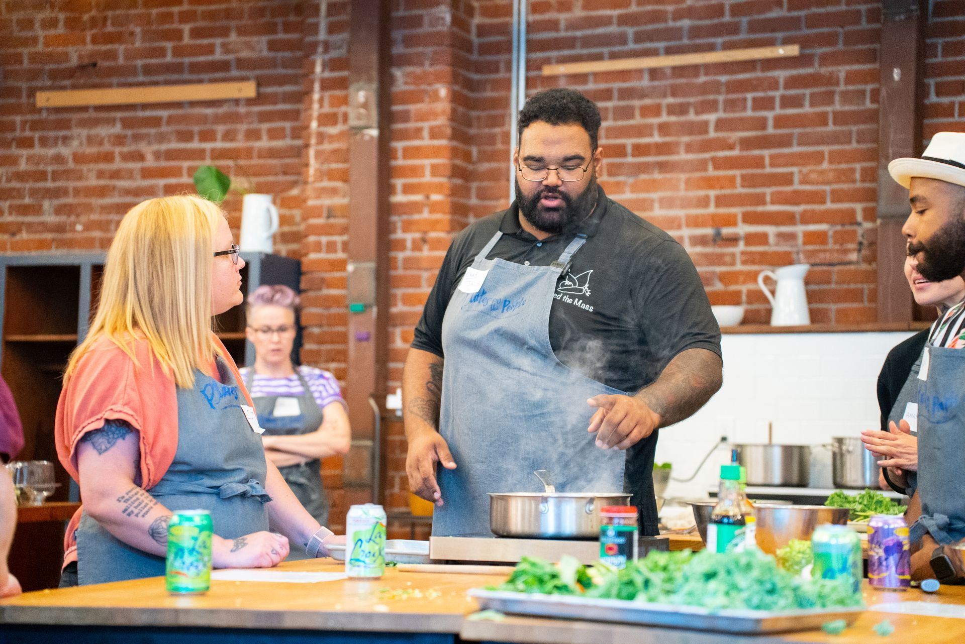 Chef in apron stirring pot on stove; cooking class in a kitchen.
