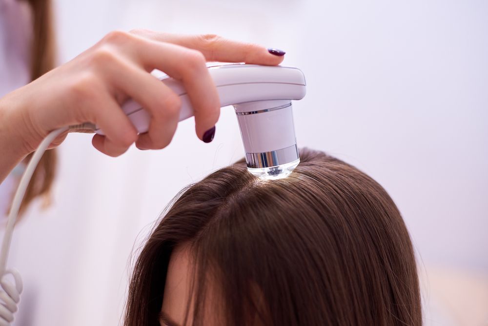 A Woman's Scalp Being Examined With a Handheld Device — Bespoke Longevity and Aesthetic Medicine In Southport, QLD