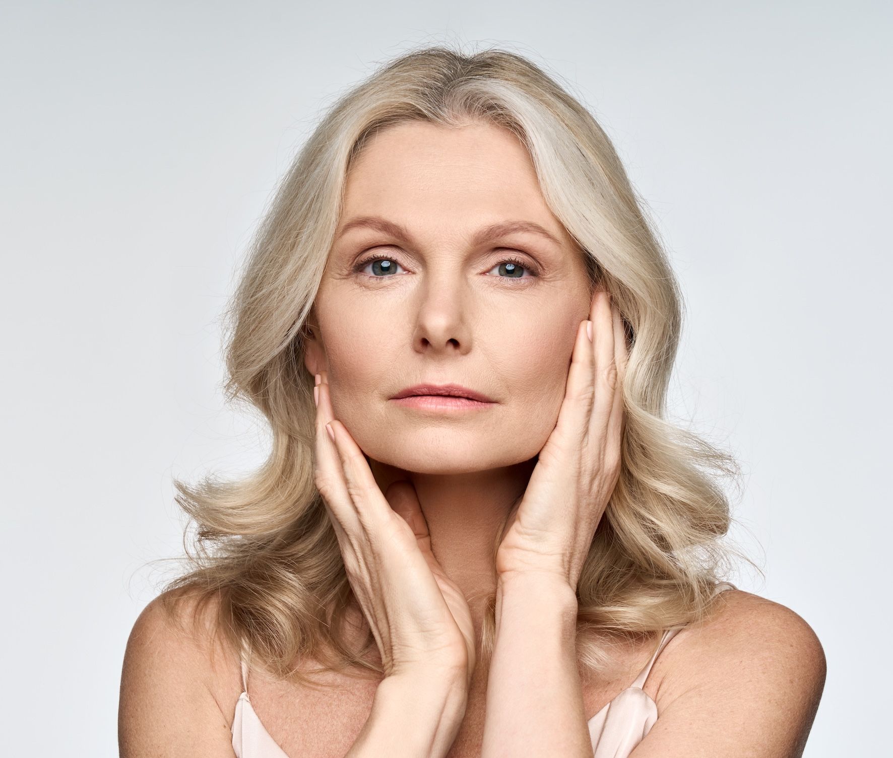 An Older Woman With Her Hands To Her Cheeks — Bespoke Longevity and Aesthetic Medicine In Southport, QLD