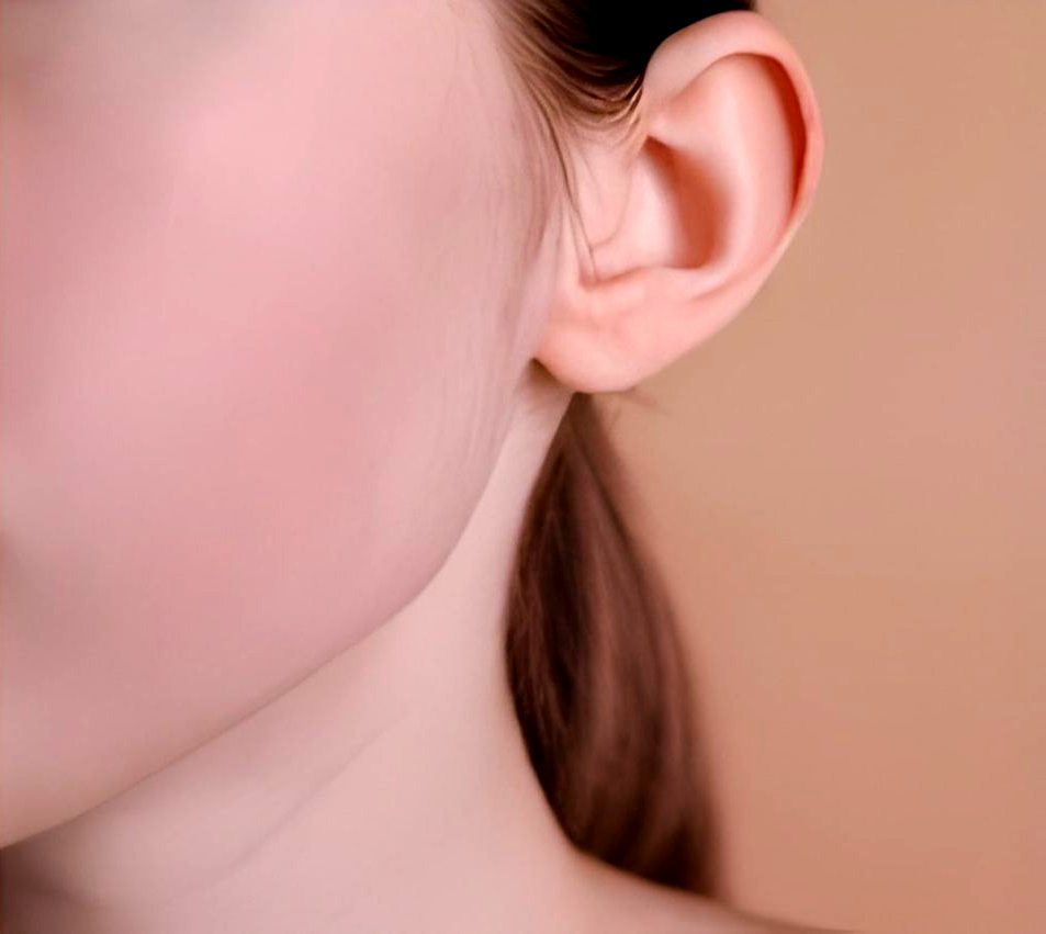 Close-up of a person's ear and neck. Skin tone is light pink with brown hair.