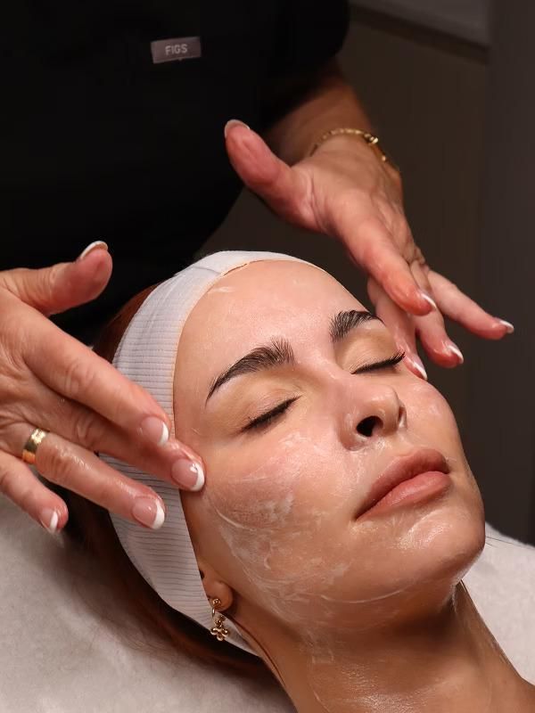 A Woman Is Getting a Facial Treatment with Her Eyes Closed — Bespoke Institute In Southport, QLD