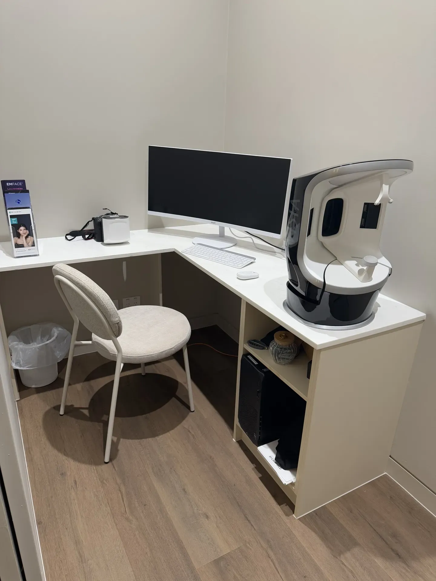 Corner workstation with a computer, diagnostic equipment, and a chair in an exam room.