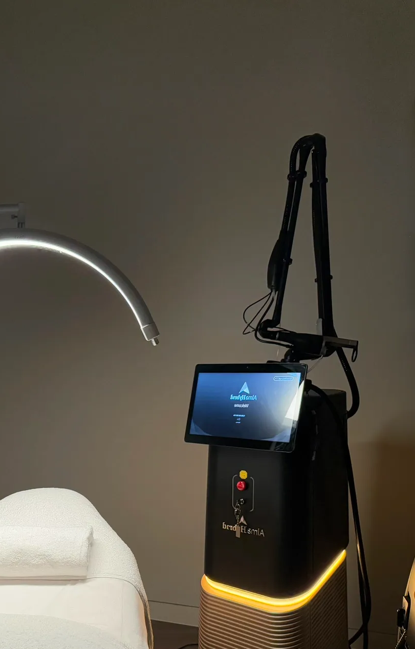 Laser machine with touchscreen in a spa setting, with an arched lamp and treatment bed.