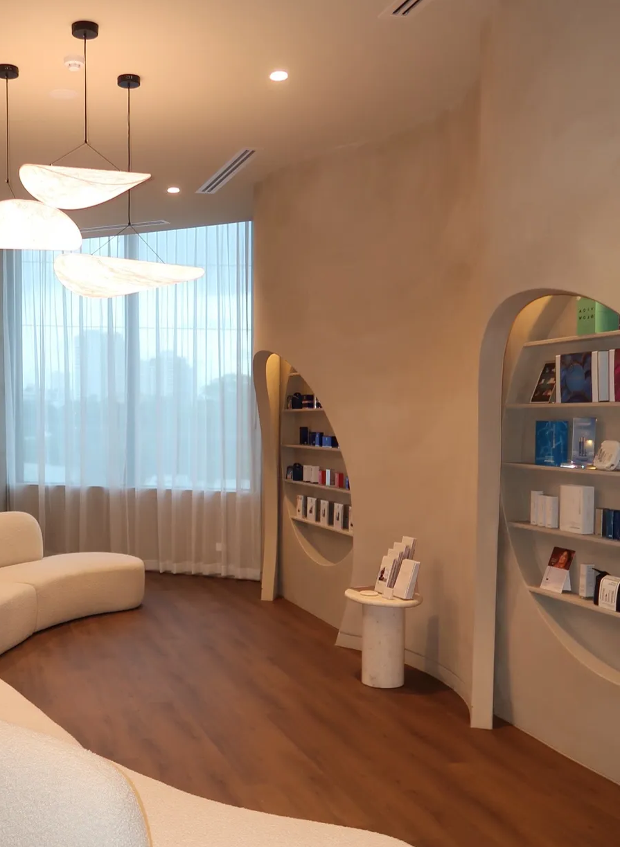 A skincare store interior with curved walls, shelves of products, and a white sofa near a window with sheer curtains.