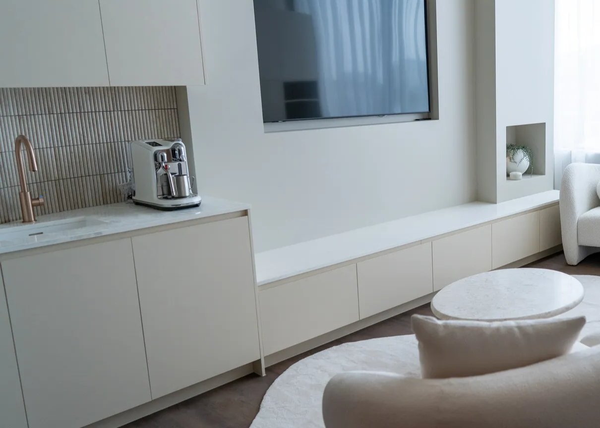 Cream-colored built-in entertainment center with a TV, a coffee station, and a seating area.