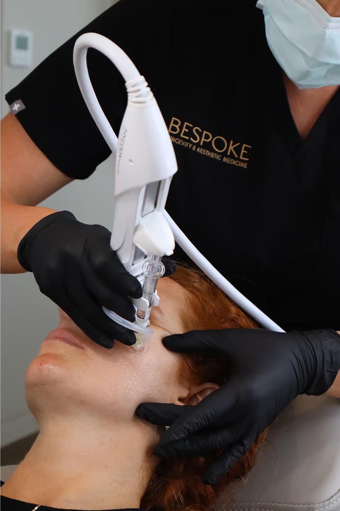 A Woman Wearing Black Gloves Is Getting a Treatment on Her Face — Bespoke Institute In Southport, QLD