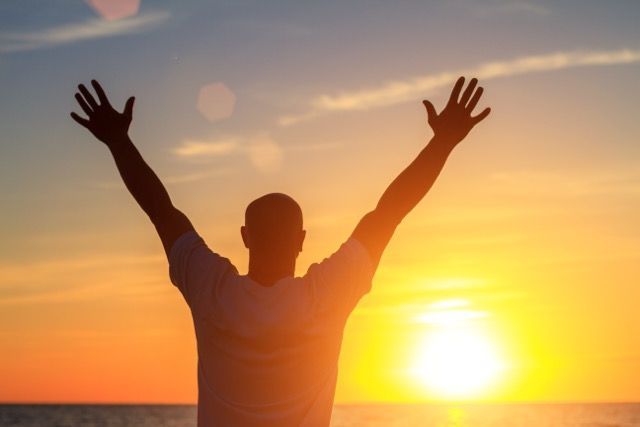 A Man Standing Facing Sunset With His Arms in The Air — Bespoke Longevity and Aesthetic Medicine In Southport, QLD
