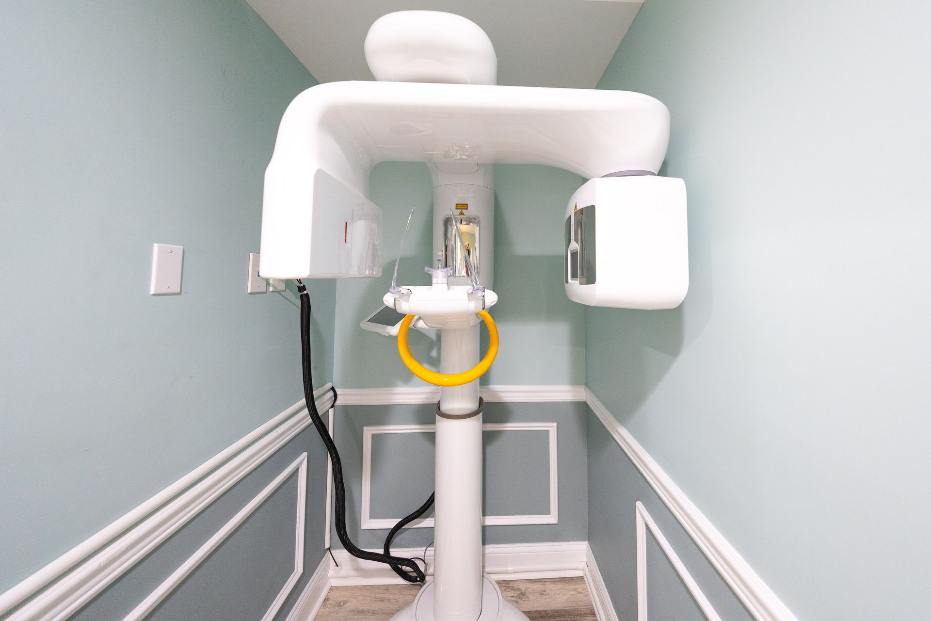 Panoramic dental X-ray machine in a light blue room with molding.