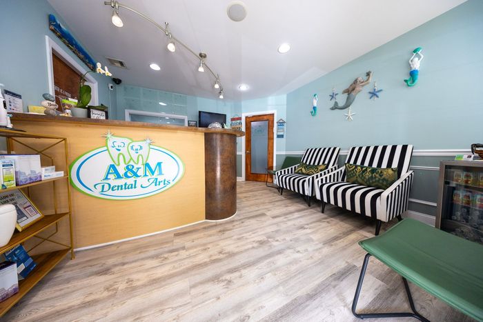 Dental office waiting room with a light blue and beige color scheme. Reception desk, striped couch, and mermaid decor.