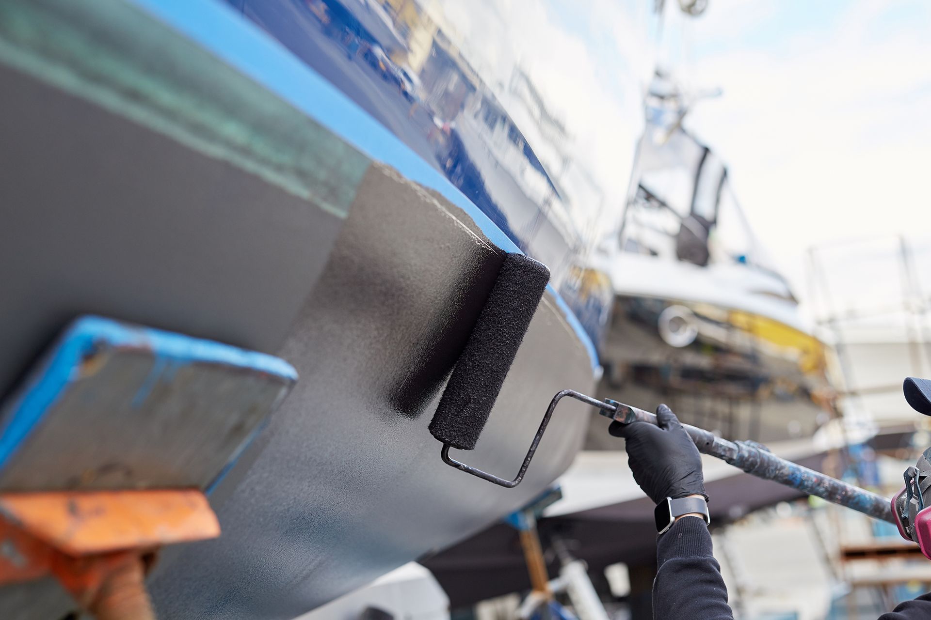 Person Painting a Boat With Roller