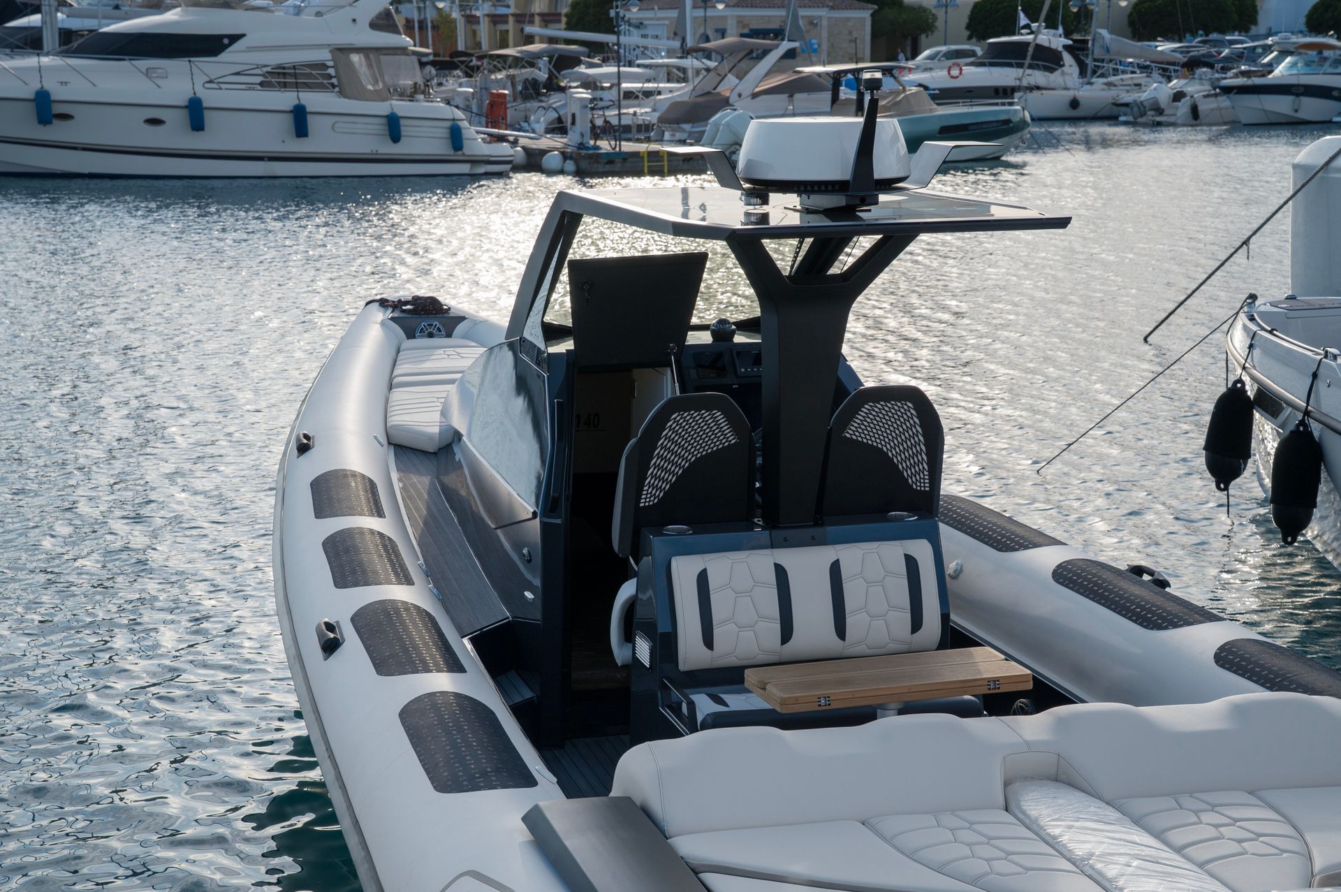 White inflatable boat in a marina with yachts and rippling water in the background