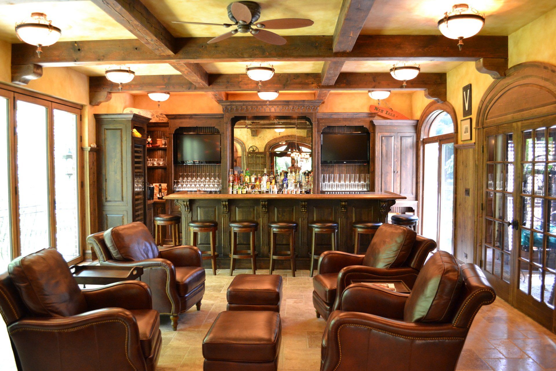 A luxurious home bar with brown leather seating, wooden bar, and decorative lighting.
