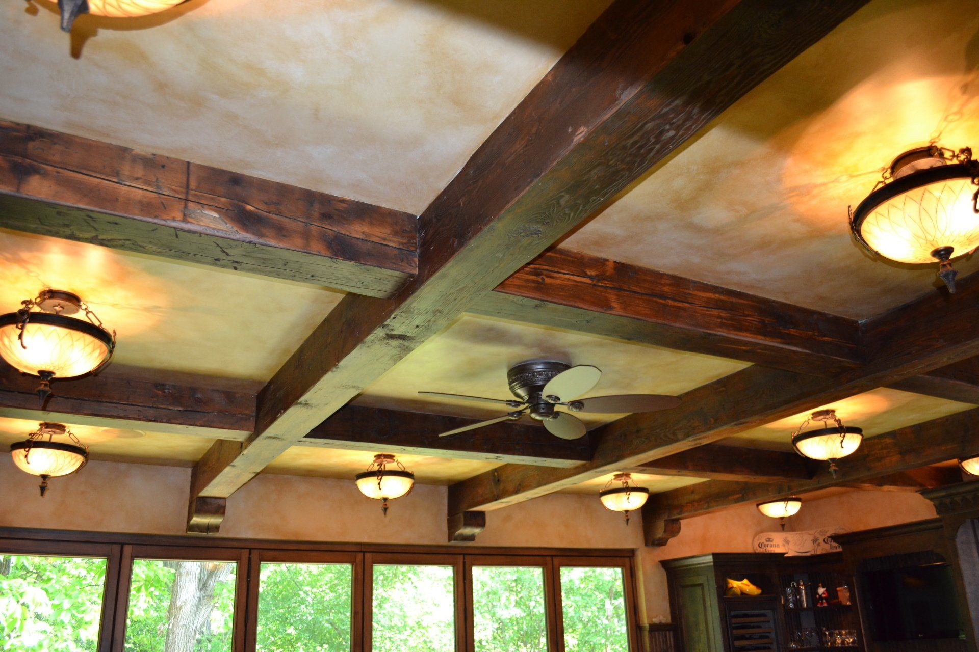 Rustic ceiling with dark wooden beams, inset lights, and a ceiling fan.