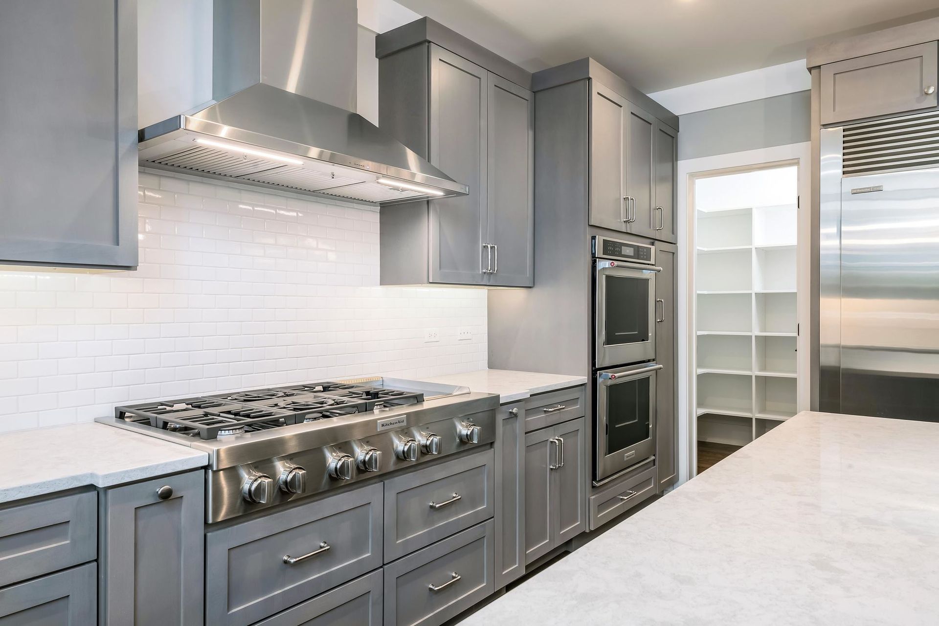 Gray and white kitchen with stainless steel appliances and a walk-in pantry.