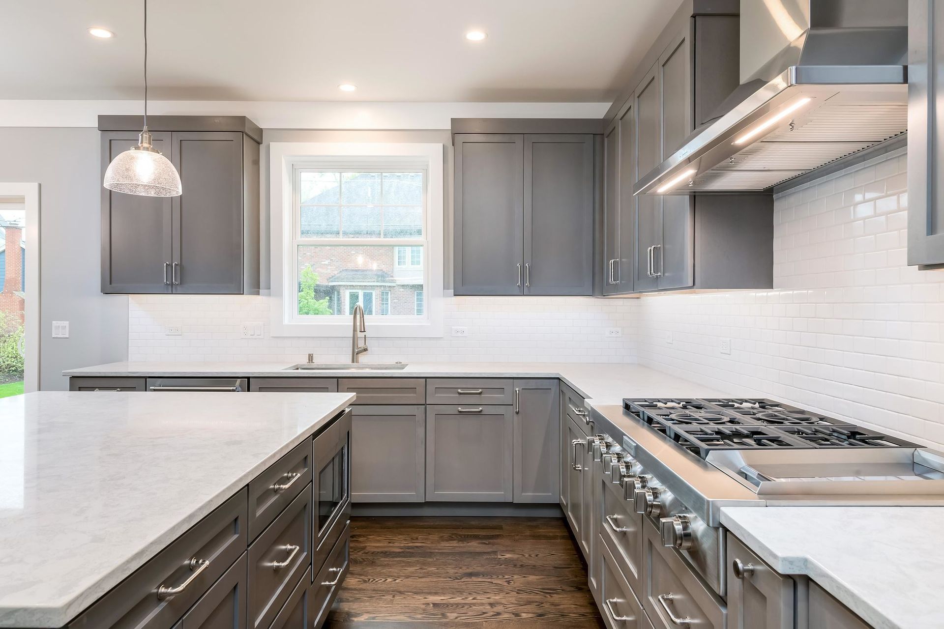 Gray kitchen with island, cabinets, stove, and white countertops.