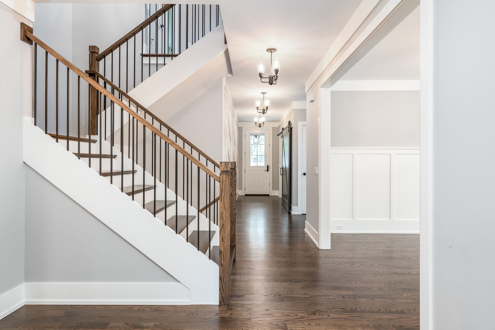 Interior hallway with staircase, dark wood floors, light gray walls, and white trim.