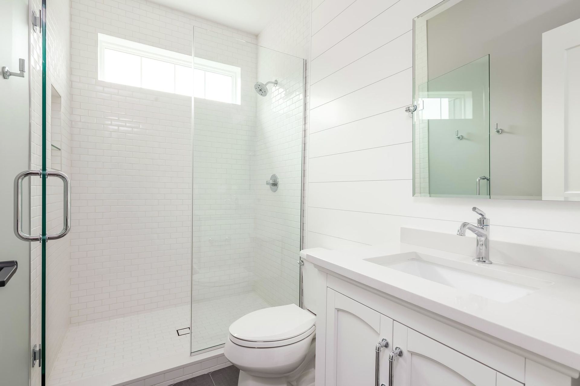 White modern bathroom with shower, vanity, and toilet.